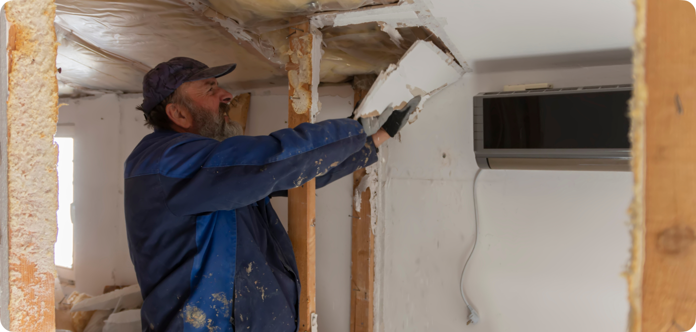 Worker repairing damaged interior ceiling materials.