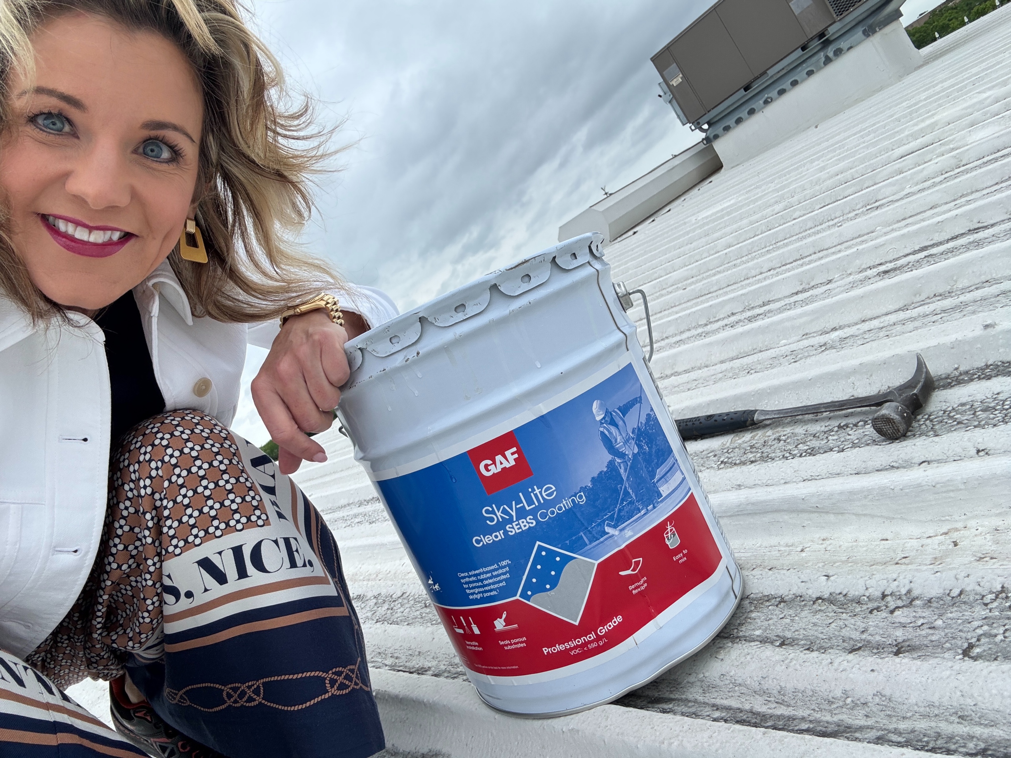 Jeanne Boyd Curtis holding GAF Sky-Lite coating on the Boyd Bone Dry roof.