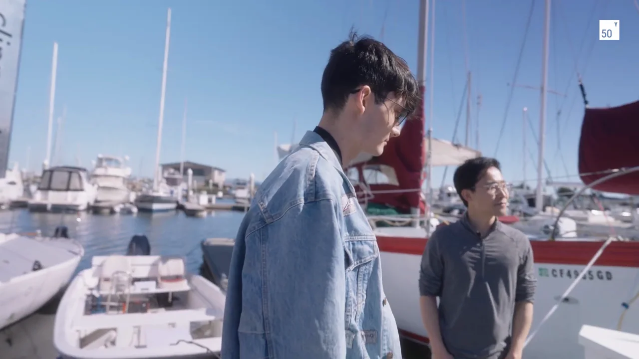 Nico Cymbalist and a colleague walk beside sailing boats in the marina.