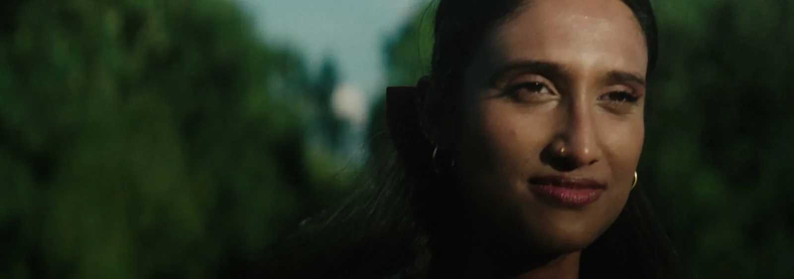 Dreamer - A young woman looks ahead in dappled green light.