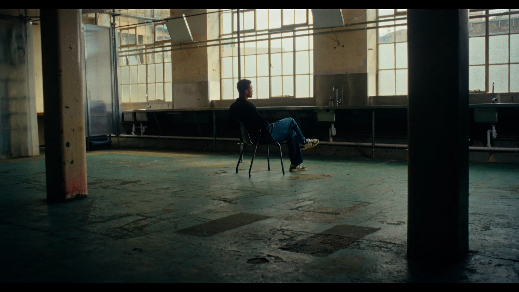 Indispensable - A solitary figure in a vast, sunlit industrial workshop