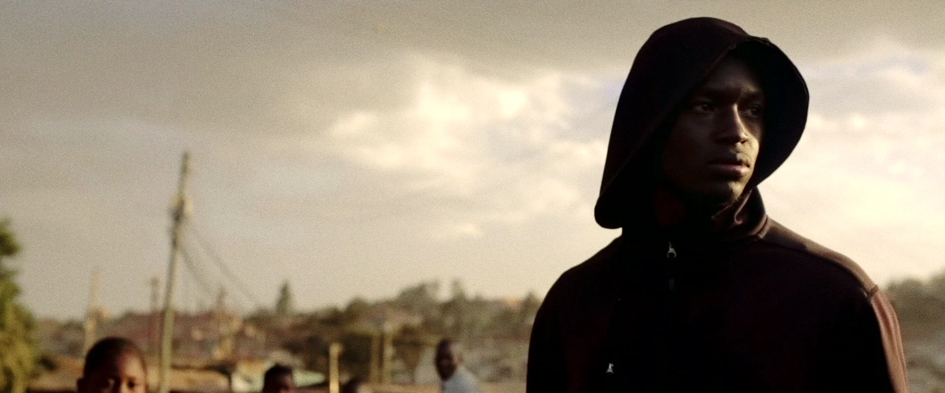 Dark Rising - a young man in a dark hood against a sunlit Nairobi skyline