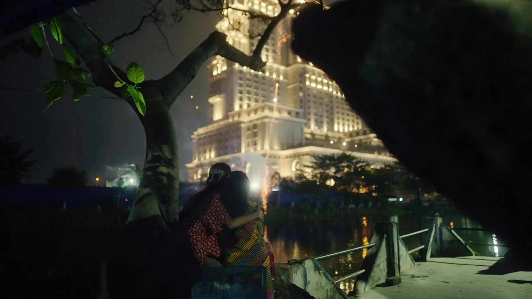 Kali - Two figures beside a brightly lit building at night