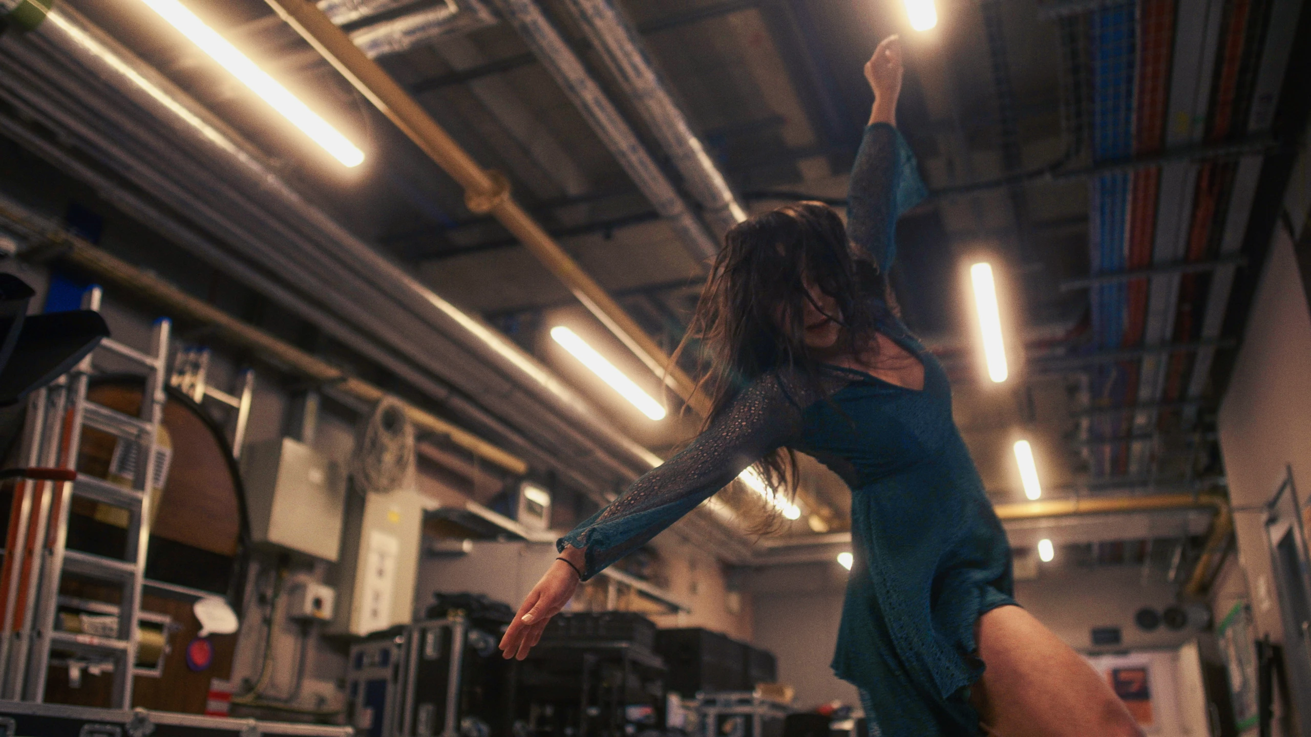 A dancer reaches into the light beneath the industrial roof at Depot Mayfield.
