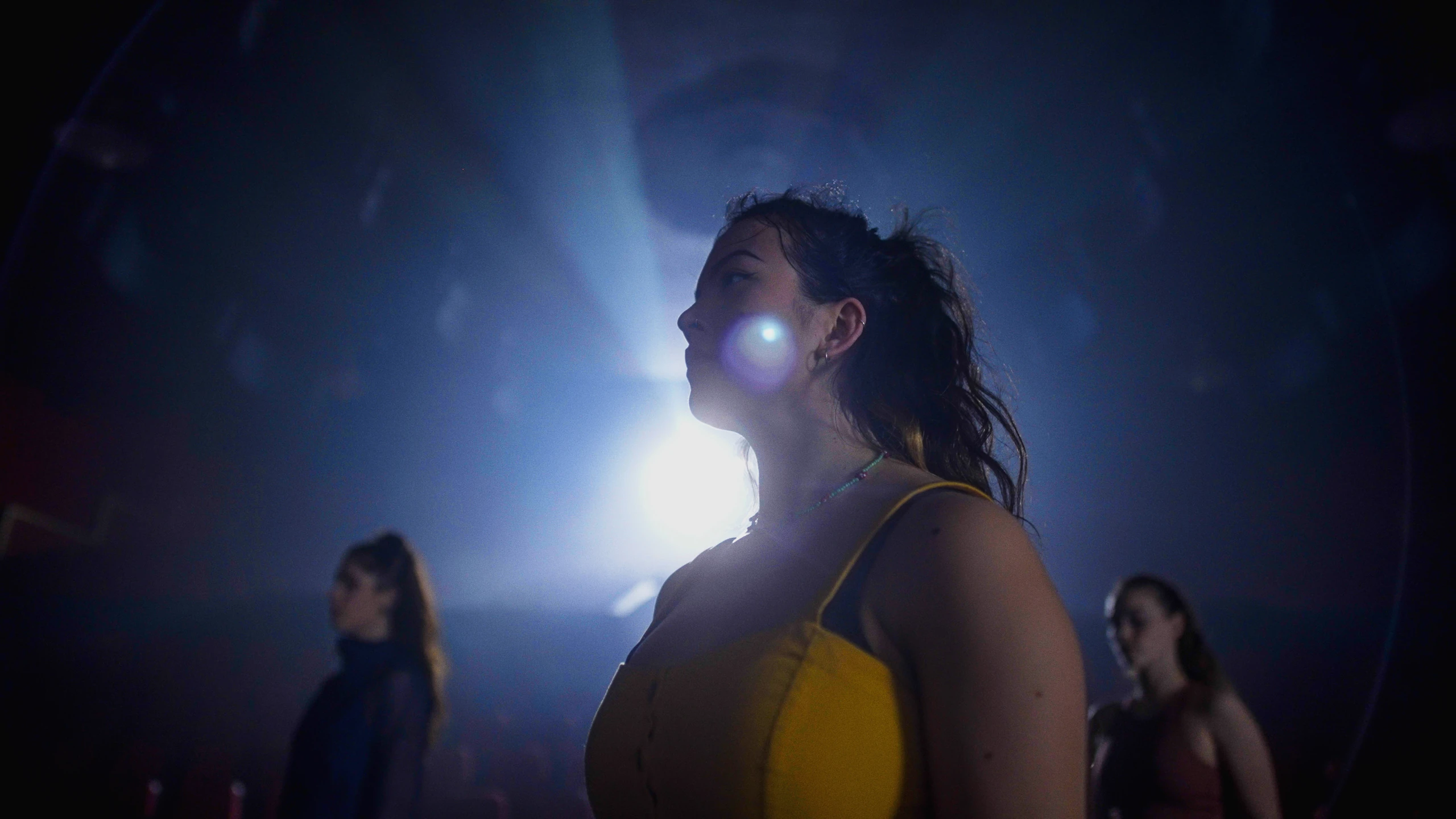 A singer in profile against a beam of stage light.