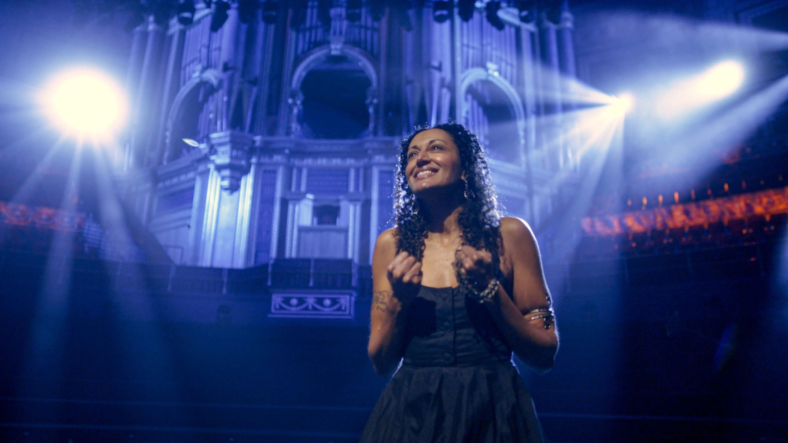 A singer in blue stage light at the Royal Albert Hall.