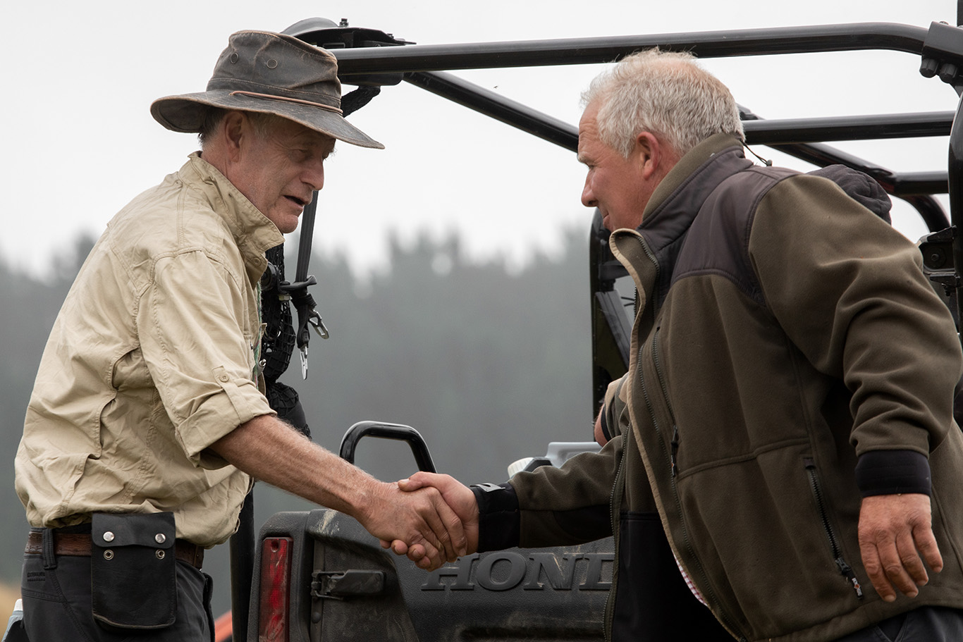 Two farmers shaking hands in a paddock