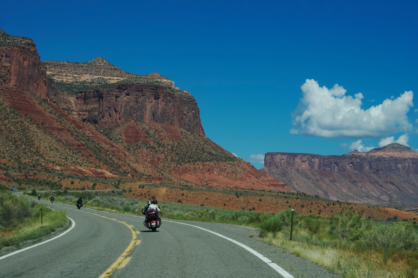Motards sur une route sinueuse dans le Colorado avec mesas rouges