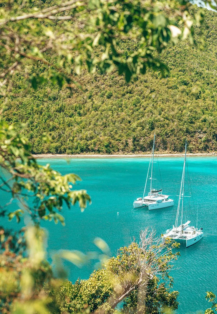 Two yachts sailing in a Caribbean bay surrounded by green hills