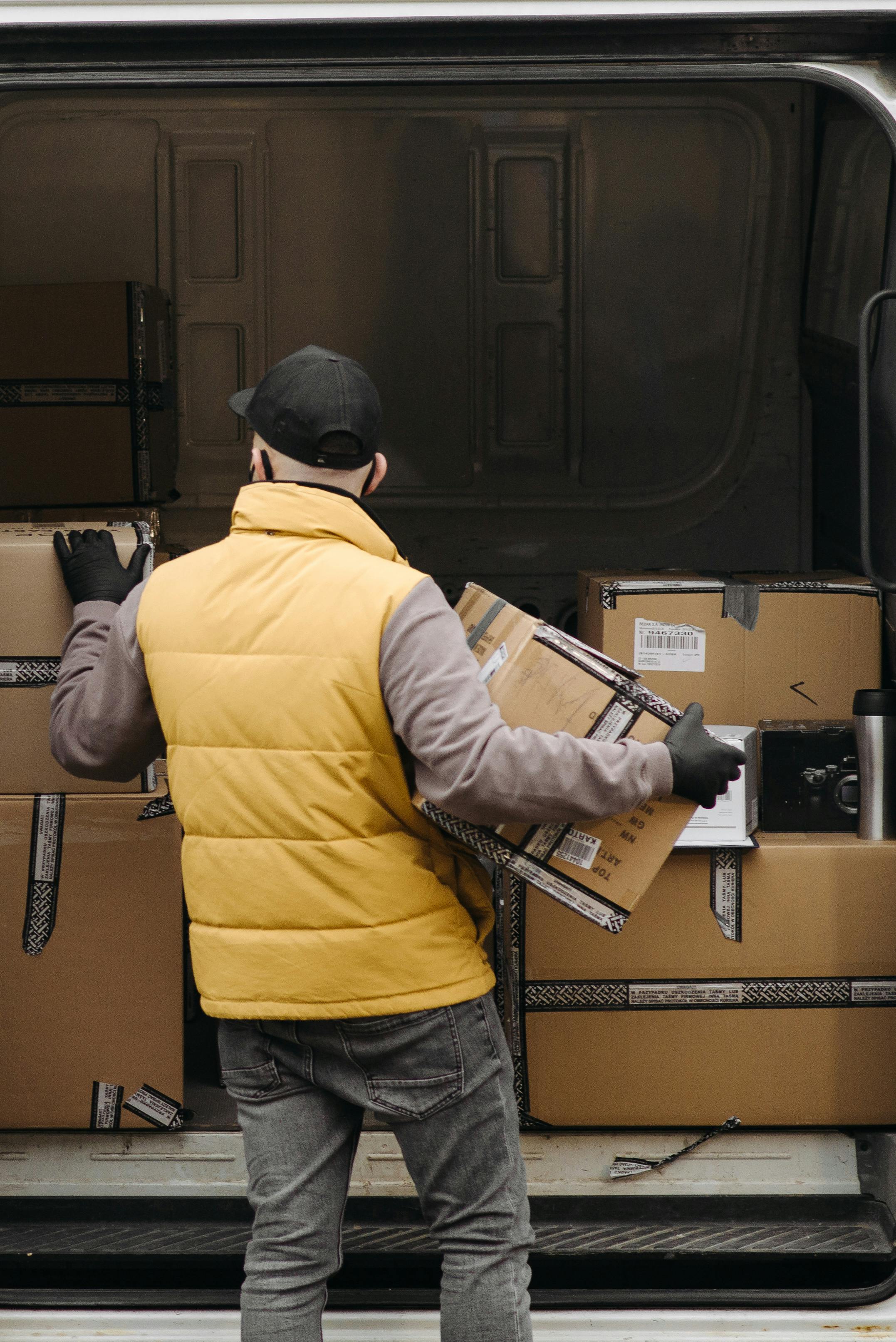 A package delivery person unloads boxes from the back of a van