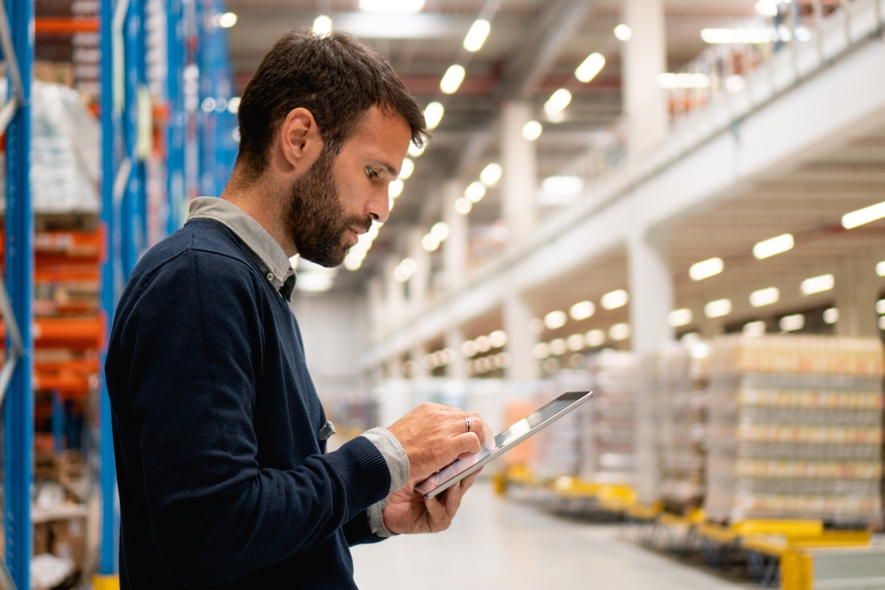 Operations manager looks at ipad in warehouse