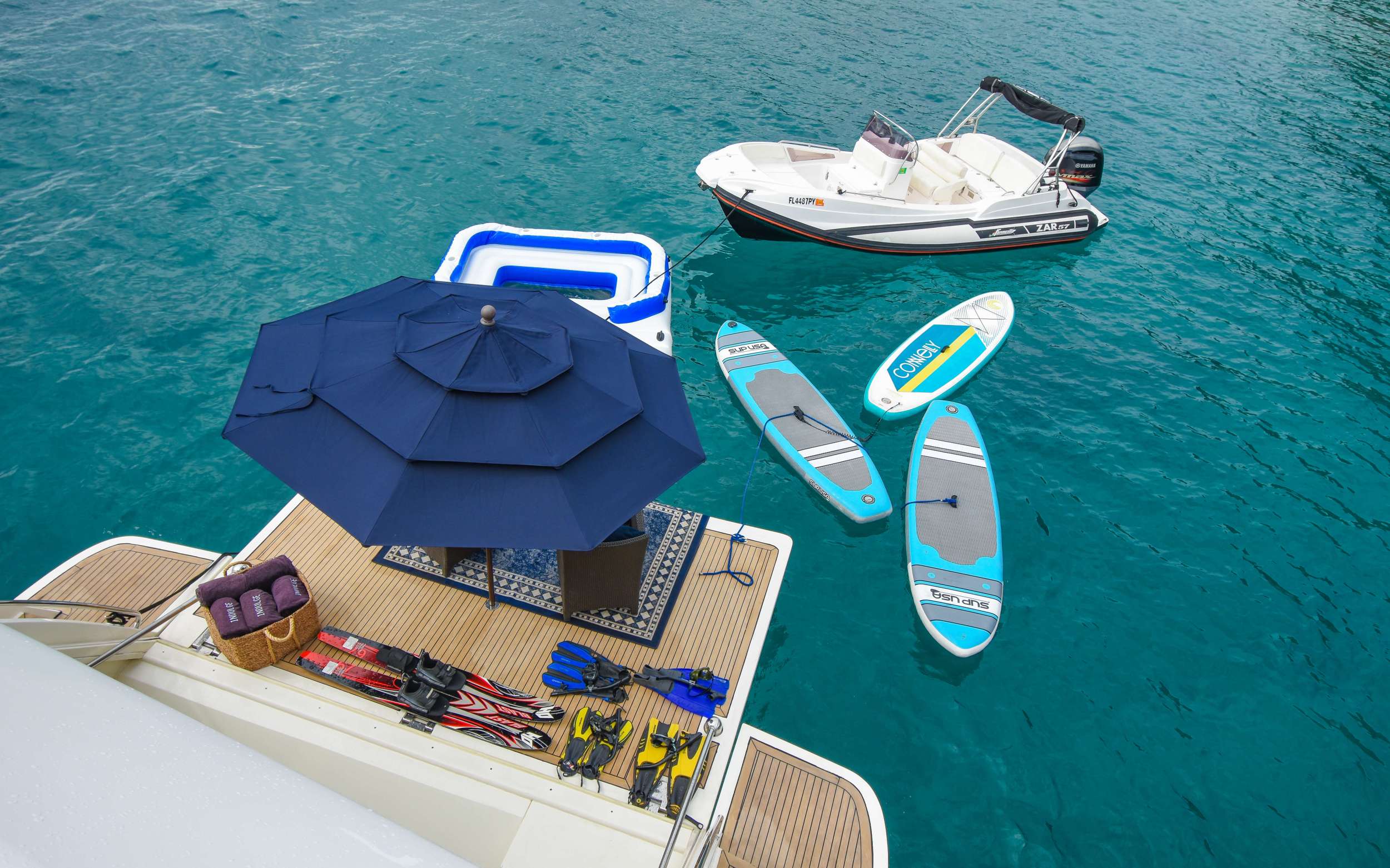 Water toys ready beside a crewed yacht: paddleboards and a jet ski
