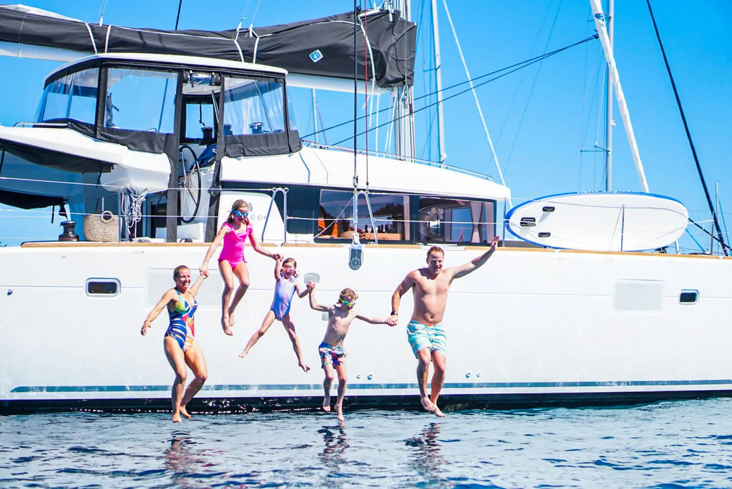 Family of five jumping into the sea from their private yacht