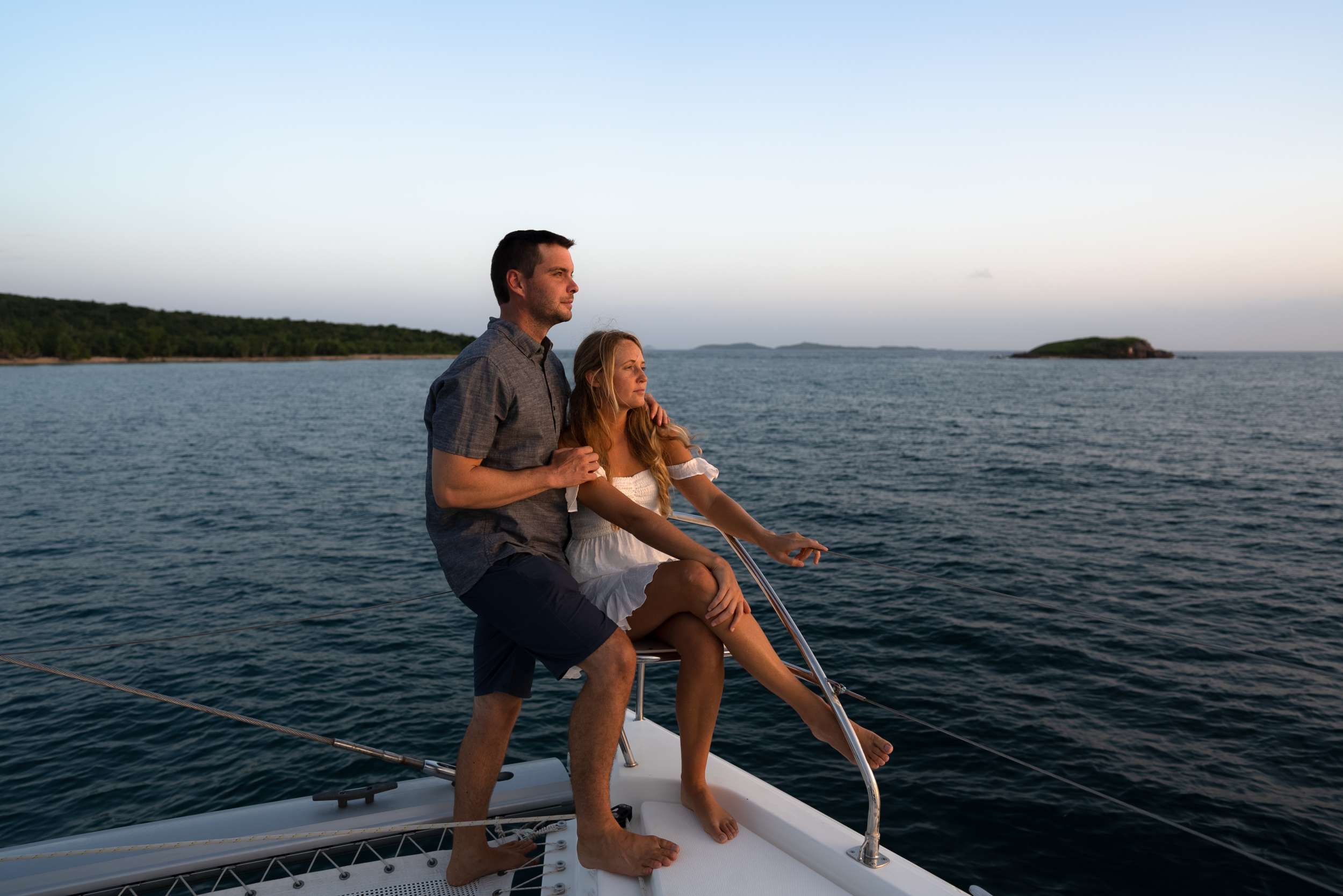 Couple watching the sunset from the bow of a crewed catamaran