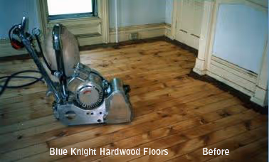 Floor sanding machine on unfinished hardwood floor in a room corner before refinishing.