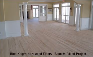 Spacious room with light-colored hardwood floors, white columns, and large windows letting in natural light.