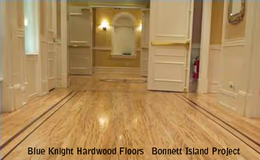 Polished hardwood floor in a bright hallway with open white doors and beige walls.