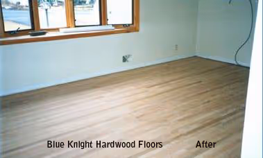Empty room with newly installed light-colored hardwood floors and a window with brown trim.