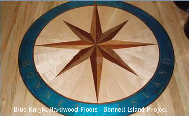 Wooden compass rose inlay with blue outer ring on a hardwood floor.