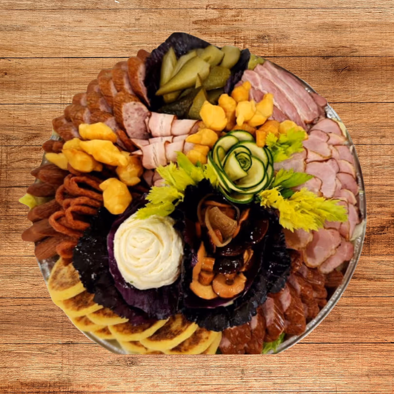Round platter with assorted sliced meats, pickles, cheese curds, nuts, garnished with cucumber rose and celery leaves on wooden table.