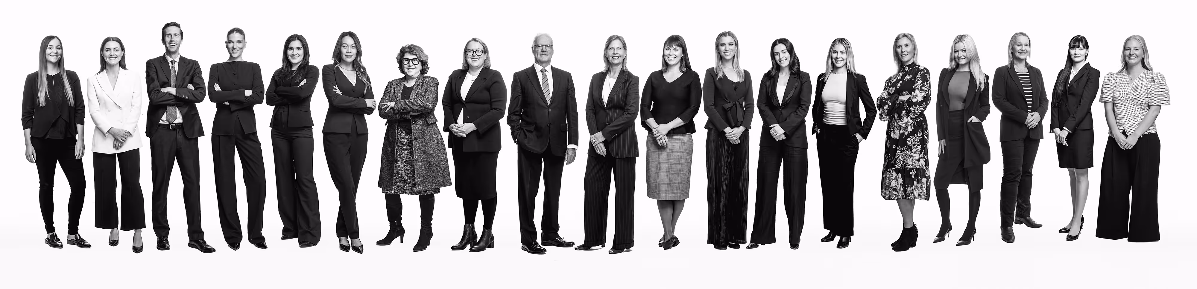 Black-and-white group photo of the Carew Counsel Solicitors team, a diverse group of professionals in business attire standing side by side and facing forward against a plain background.