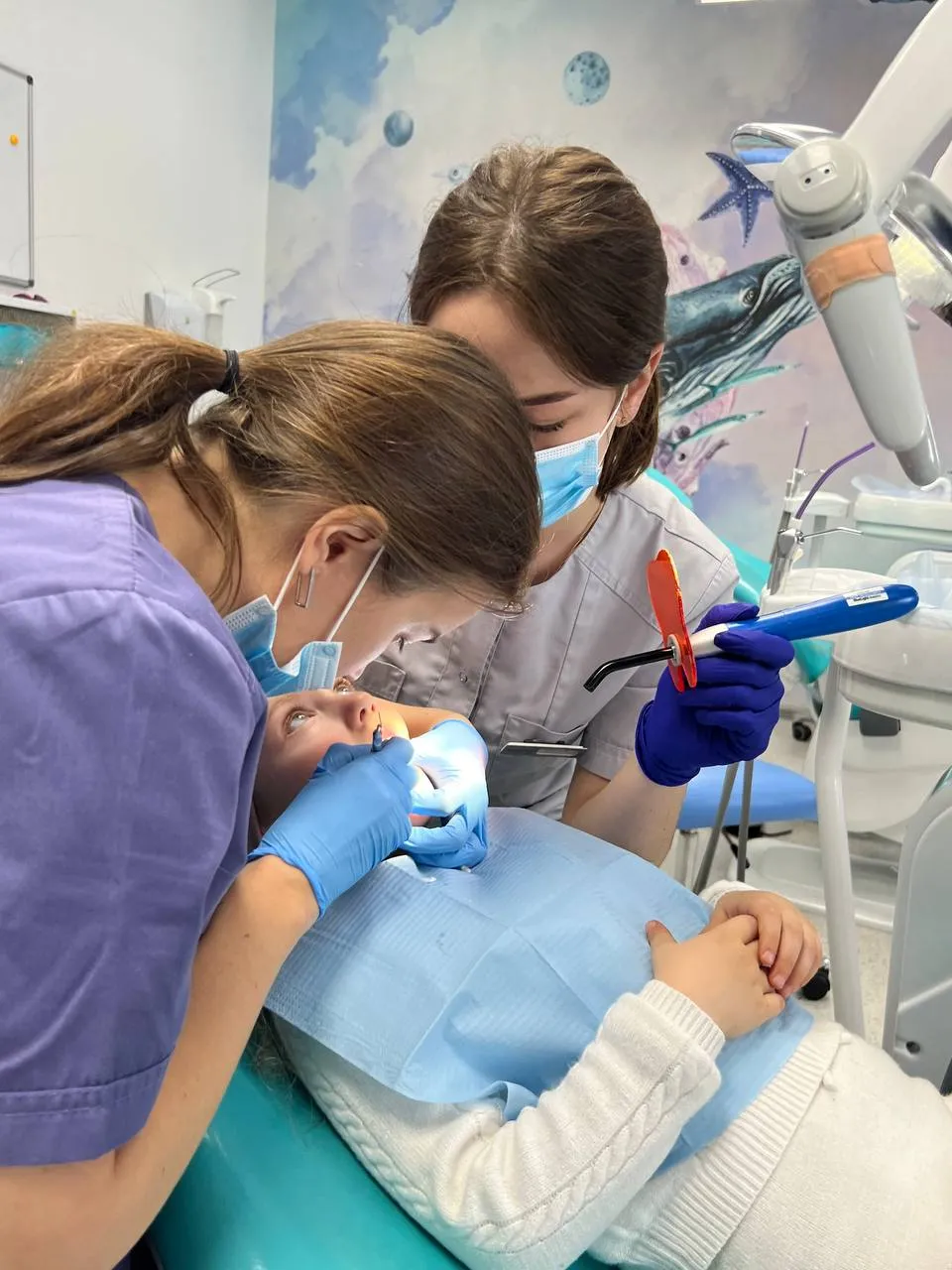 A woman in a dentist's chair with a child.