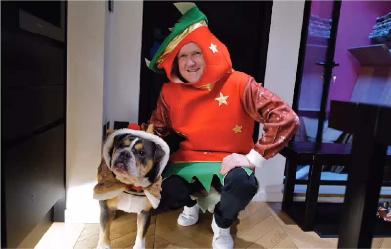 Team in festive Christmas jumpers during a Secret Santa lunch celebration, smiling and holding gifts.