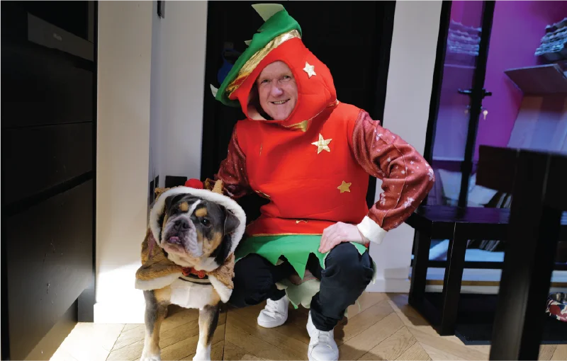 Team in festive Christmas jumpers during a Secret Santa lunch celebration, smiling and holding gifts.