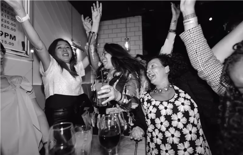 Distinct team Christmas party with colleagues smiling, dancing, and celebrating together in a lively venue.