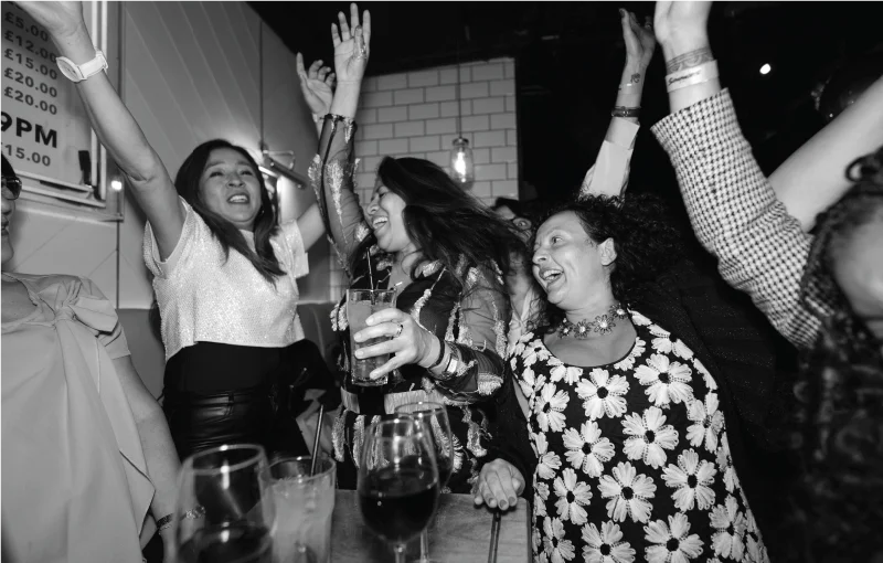 Distinct team Christmas party with colleagues smiling, dancing, and celebrating together in a lively venue.