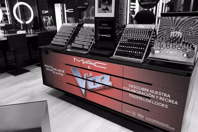 MAC makeup counter promoting collaboration with La Voz TV show, featuring various cosmetics on display.