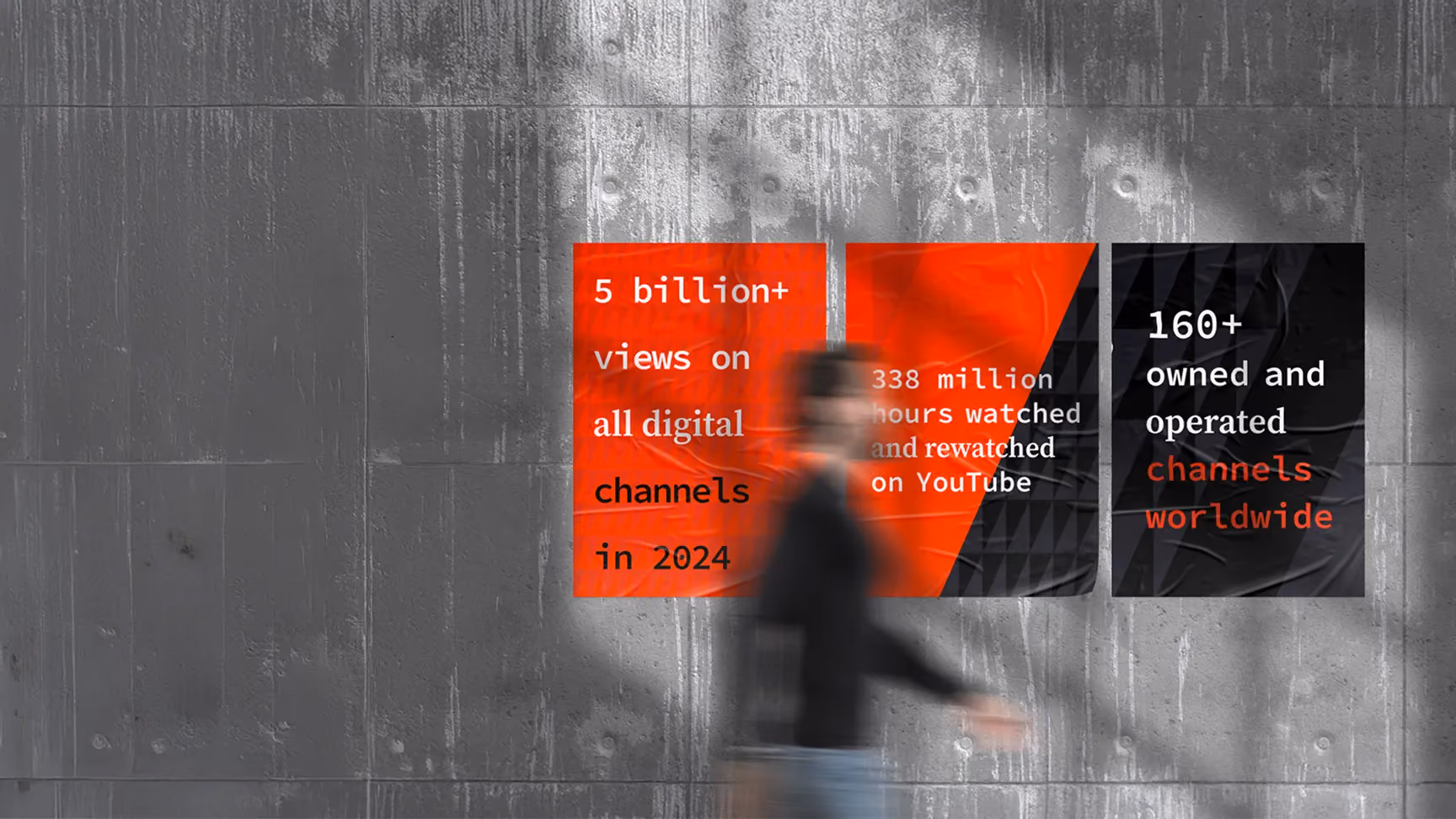 Blurred person walking past three digital stat posters on a concrete wall.