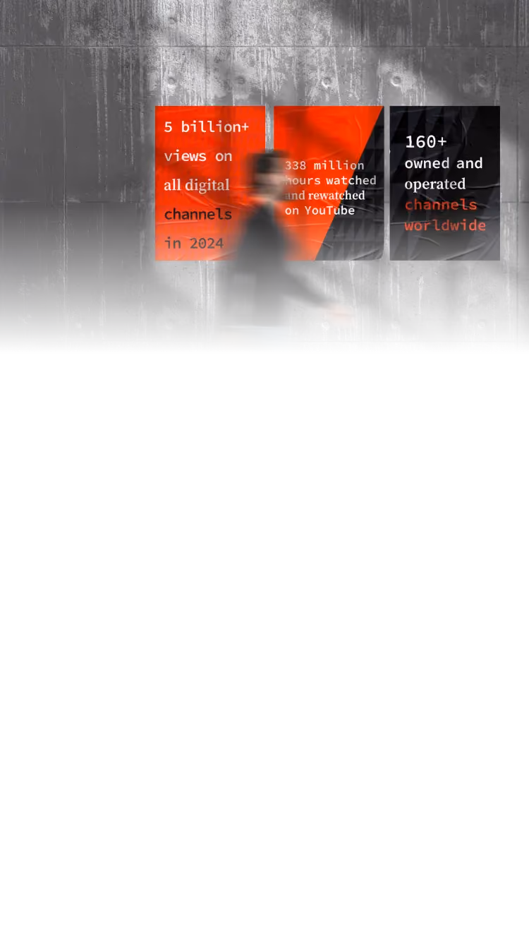 Blurred person walks past wall with three red and black posters displaying digital channel stats.
