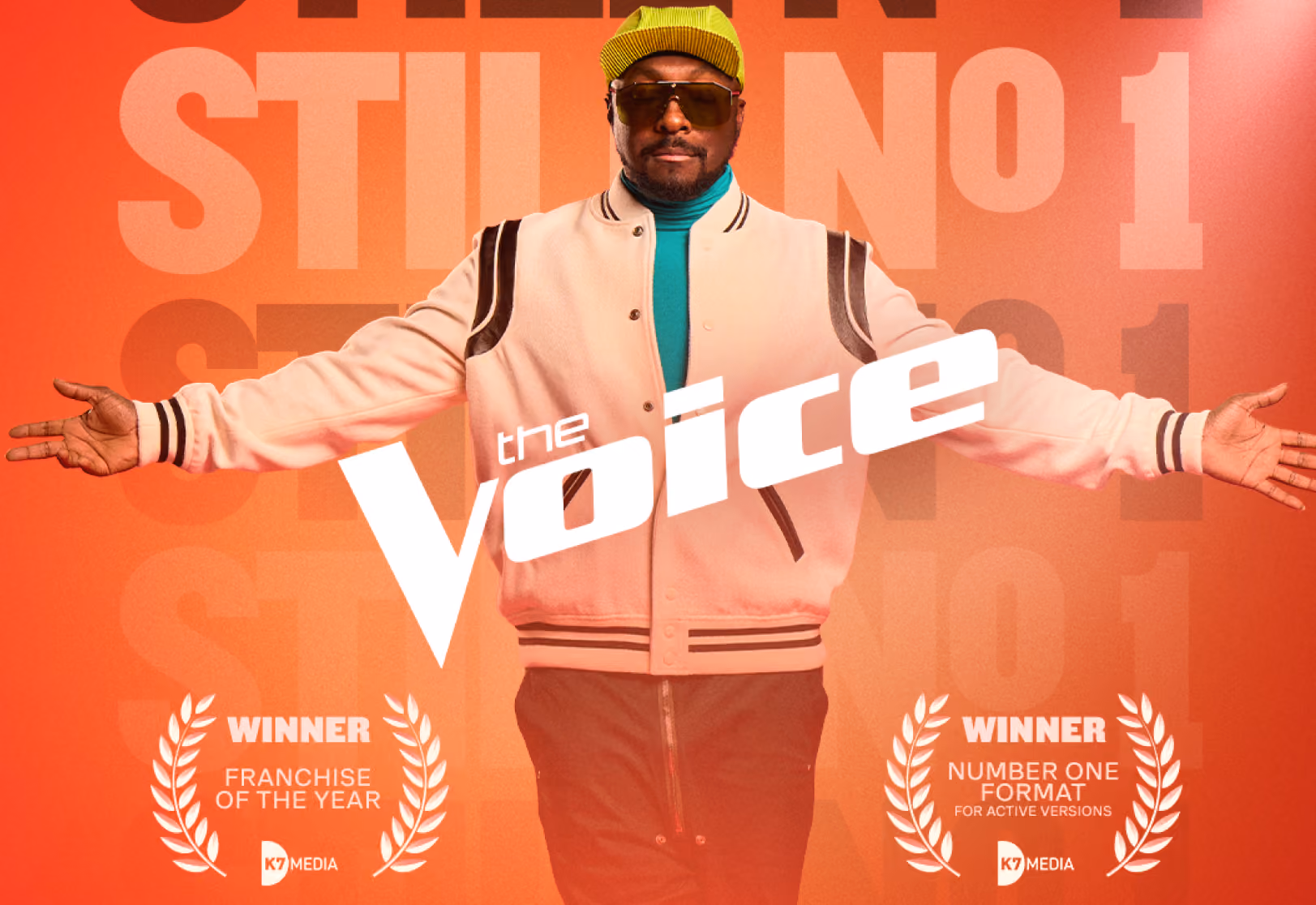 Promotional image for The Voice with coach wearing cap and jacket, flanked by award mentions in laurel wreaths.