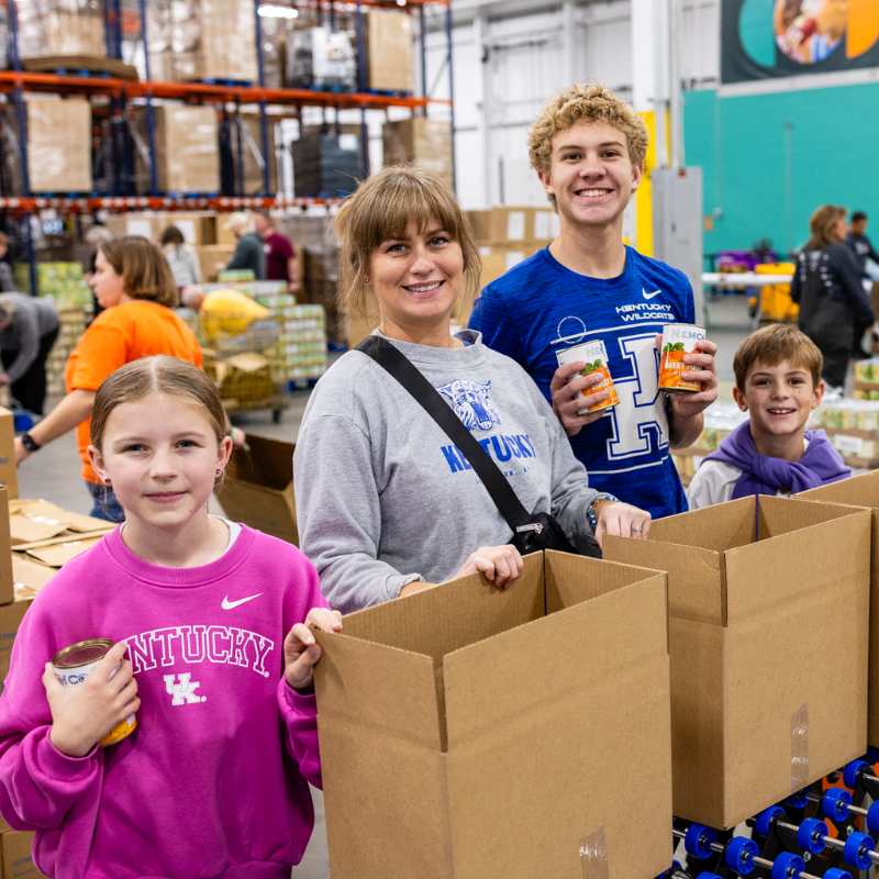 A family volunteering to pack boxes at God's Pantry Food Bank.