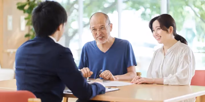 Smiling elderly man and woman meeting with a professional advisor at a desk.