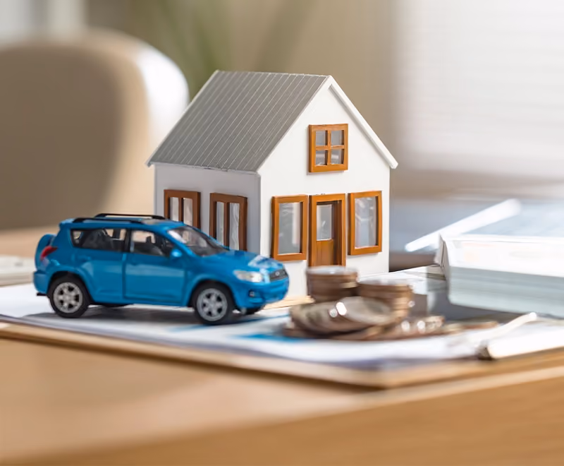 Close-up photograph of key assets such as a home, car and financial documents in divorce.