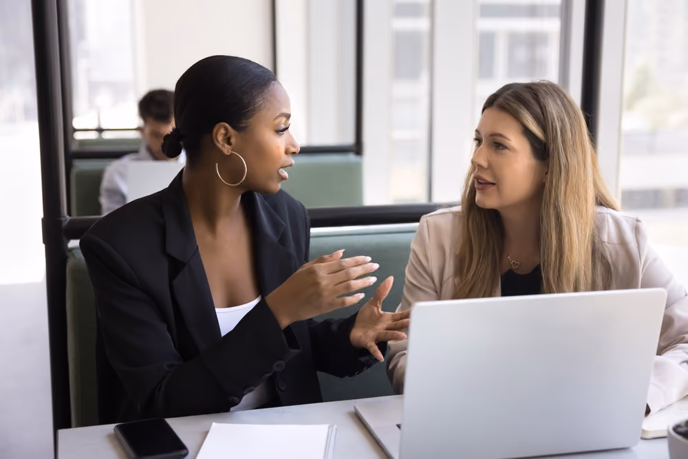 Two women sitting at a desk with legal documents, discussing and signing paperwork related to a will dispute.