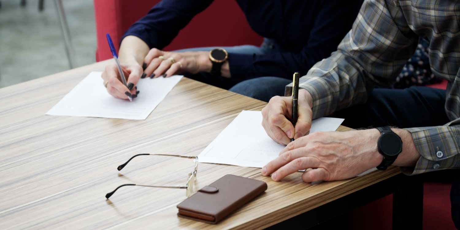 Parents signing documents to formalise parenting arrangements after separation.