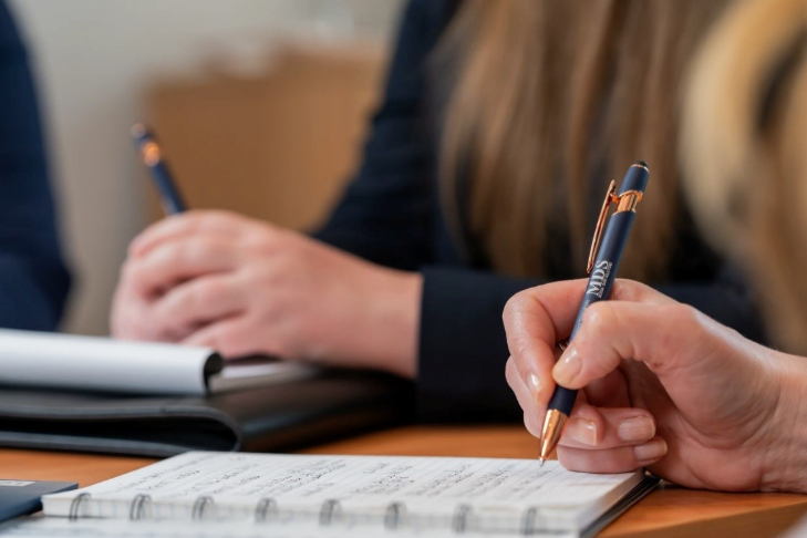 A person writing on a notebookAI-generated content may be incorrect.