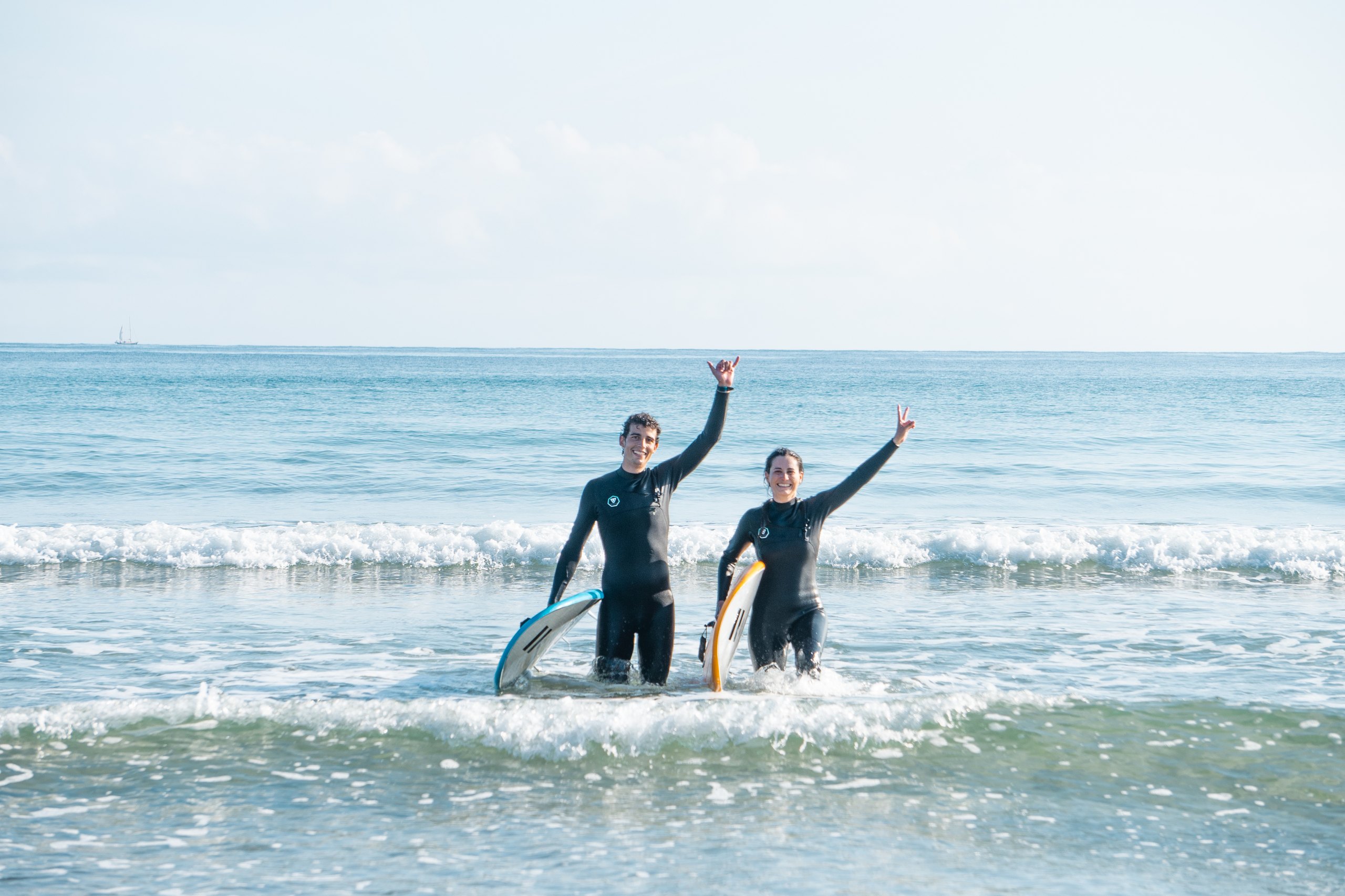 two beginners walking out of the water at oyambre after a surf lesson