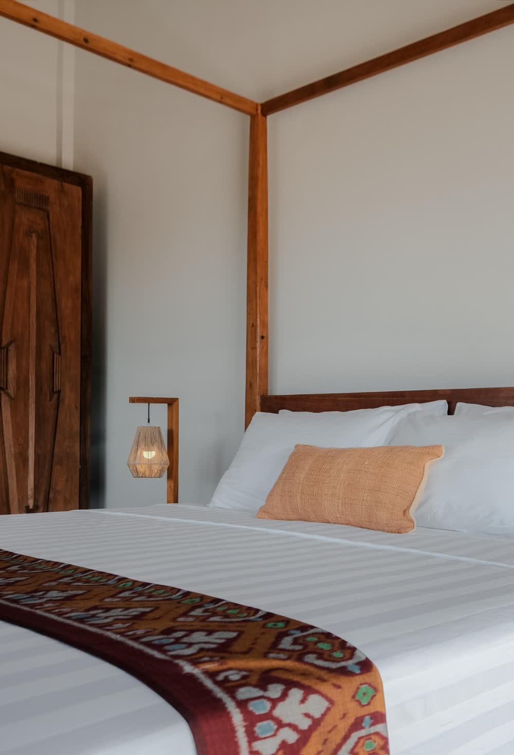a four-poster bed with a woven runner