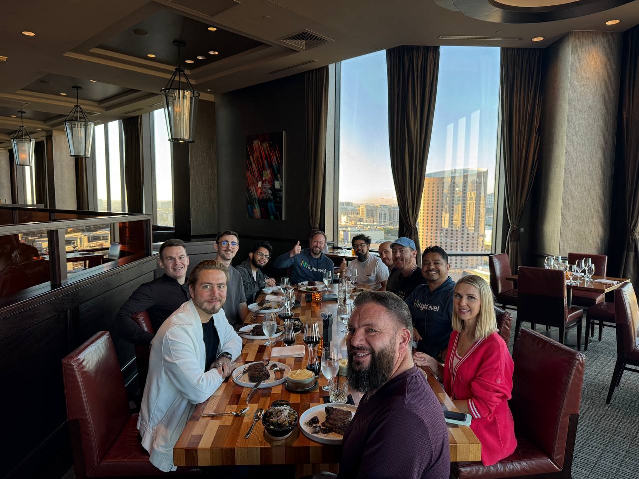 The same table mid-meal at sunset, plated steaks and the city skyline behind