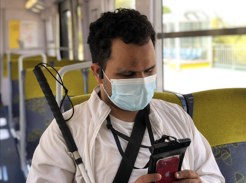 Utilisateur avec une canne assis dans le train sur son téléphone