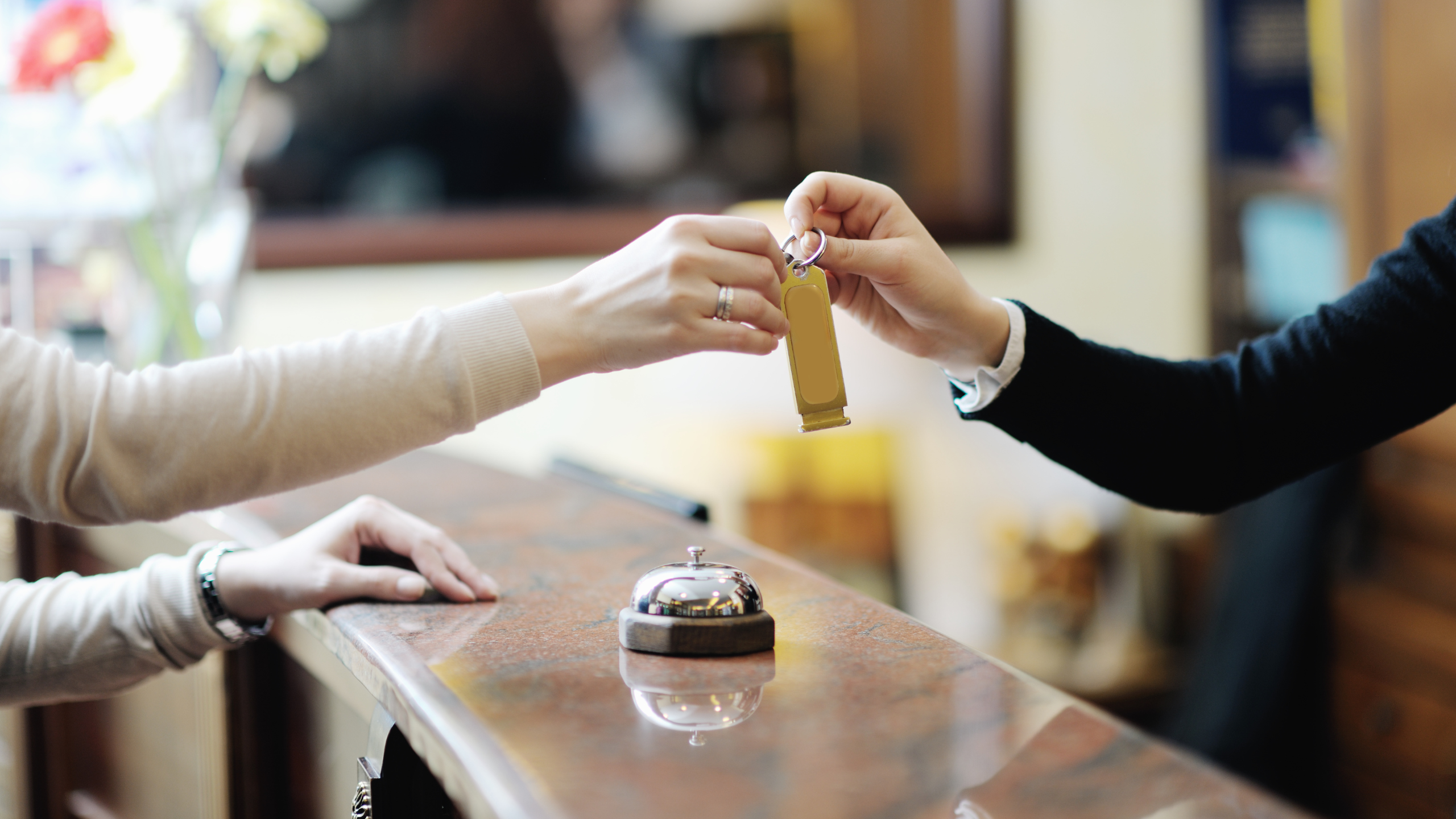 accueil d'un hôtel au comptoir avec la cloche et la réceptionniste qui donne une clé
