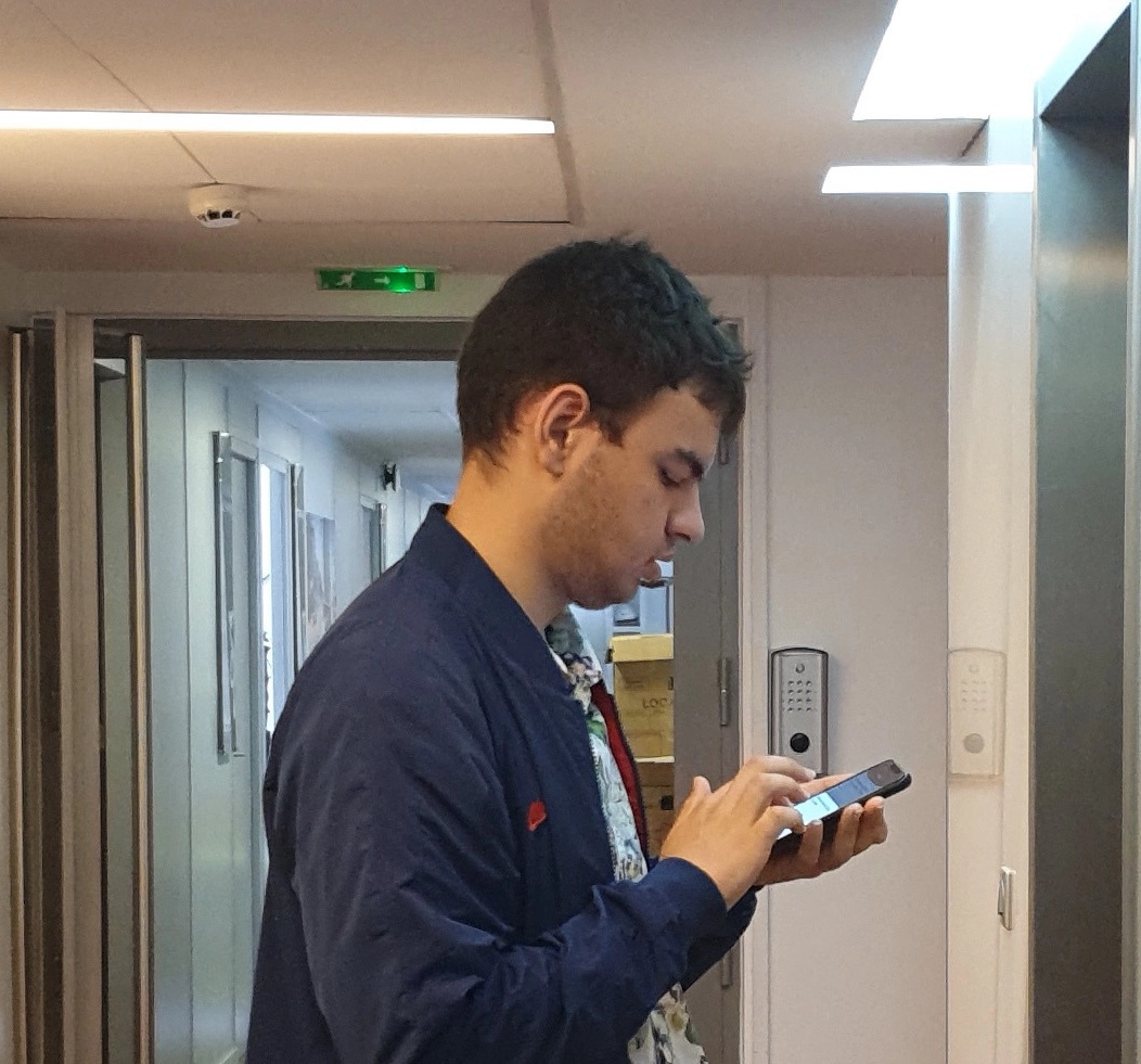 photo de Florian, utilisateur, en train d'utiliser le guidage sur son smartphone dans un bâtiment