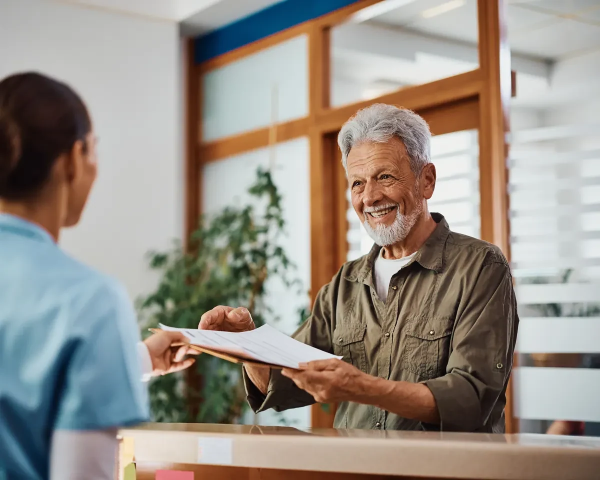 Smiling senior patient checking in at a clinic front desk