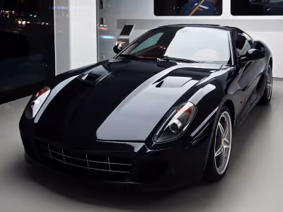 Voiture de sport noire ultra brillante garée à l'intérieur avec des reflets lumineux sur la carrosserie.