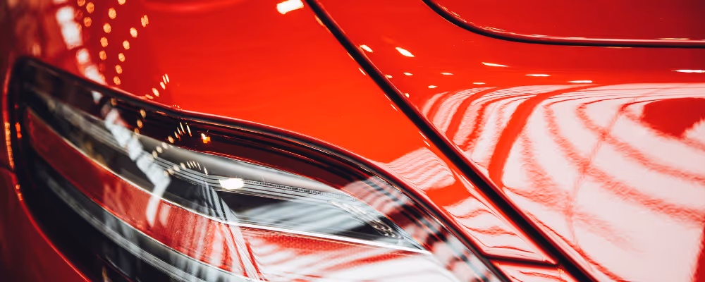 Gros plan du phare avant et de la carrosserie rouge brillante d'une voiture de sport.