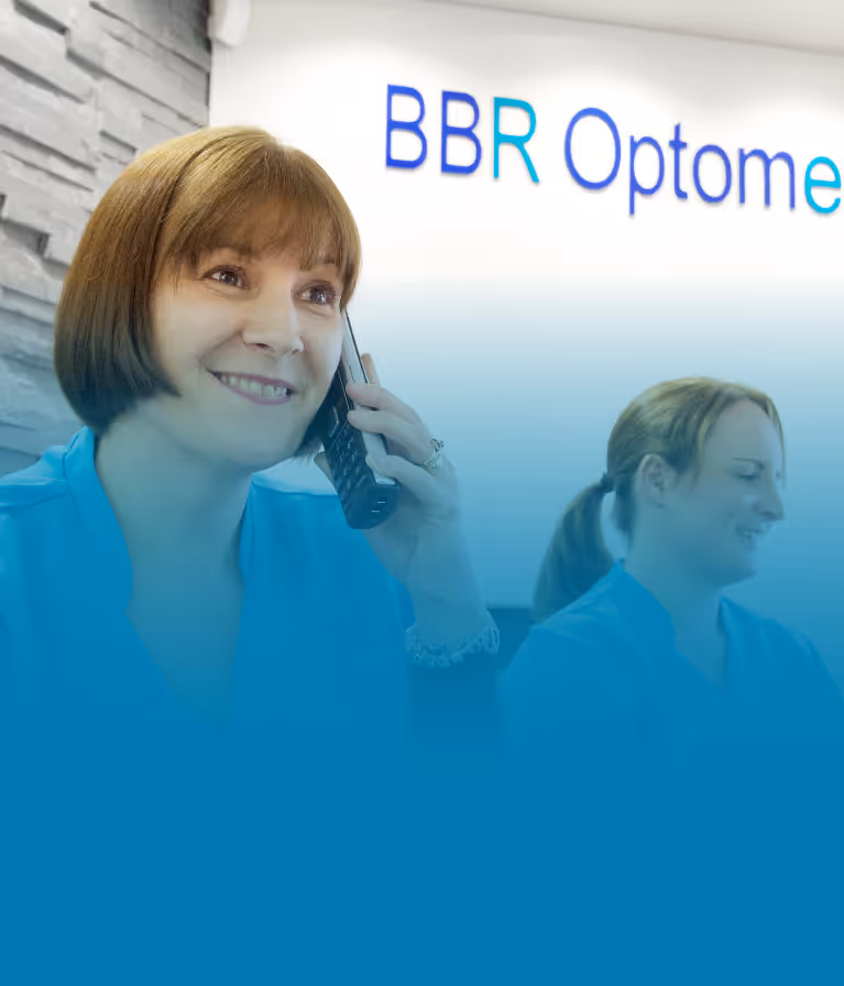 A woman talking on a cell phone in front of a sign